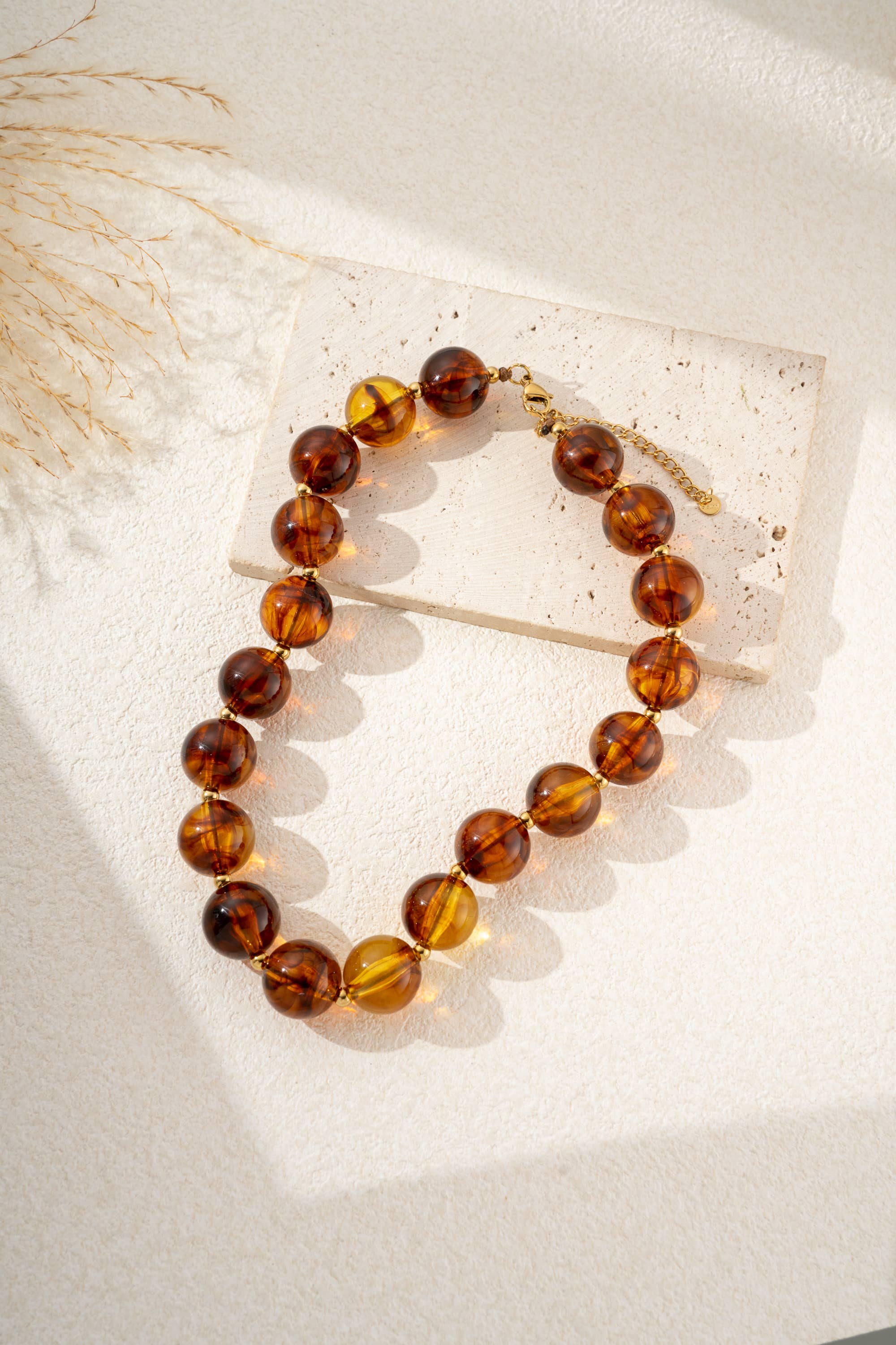 Damesketting met gouden, ronde, gemarmerde gekleurde harskralen