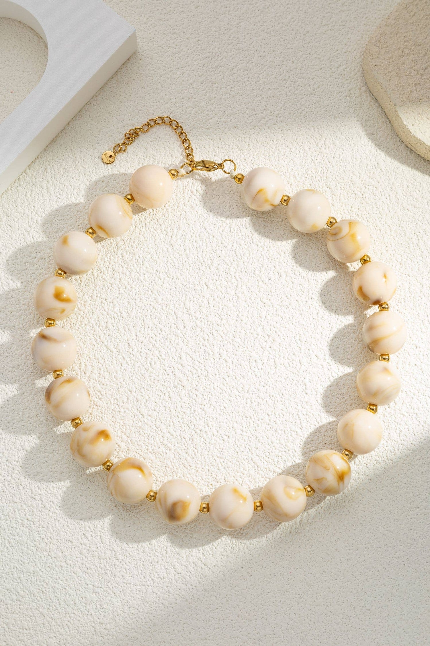 Damesketting met gouden, ronde, gemarmerde gekleurde harskralen