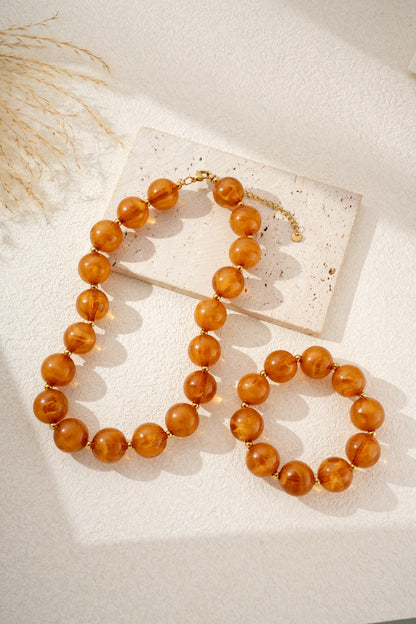 Damesketting met gouden, ronde, gemarmerde gekleurde harskralen